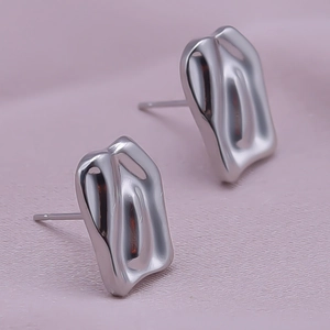 Macro shot of silver liquid metal geometric stud earrings on soft purple background