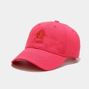 Close-up of bright orange maple leaf embroidery on a rose red cotton baseball cap