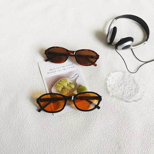 Flat lay of vintage oval sunglasses in tortoise and black frames with trendy props