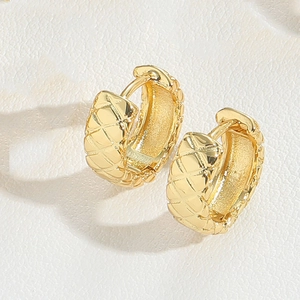 Macro shot of gold quilted hoop earrings featuring a luxury lattice pattern on metal