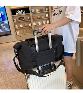 Black quilted travel bag with trolley sleeve attached to white suitcase in bookstore