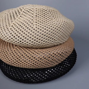 Close-up of hollow knit berets in cream, khaki, and black showing crochet mesh texture