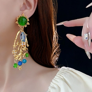 Detail von Vintage-Gold-Quastenohrringen mit grünem Harzstein und bunten Perlen