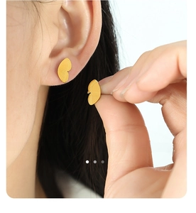 Macro view of gold butterfly wing earrings with fine radial textures on earlobe