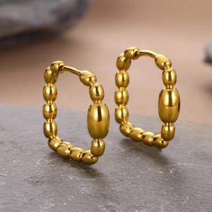 Macro detail of 18k gold plated geometric hoop earrings with beaded texture on stone