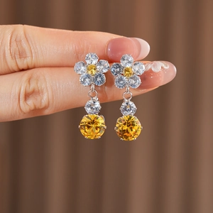 Detailed shot of silver flower earrings featuring sparkling yellow and clear zircons