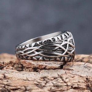 Close-up of Viking Tree of Life ring with vine textures on rustic wood surface