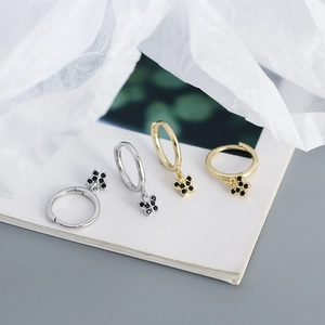 Close-up of gold and silver butterfly hoop earrings with black zircon stones on white paper