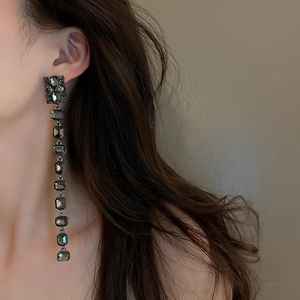 Gothic style long tassel earrings with dark square crystals on a side-profile model