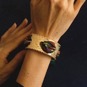 Macro shot of matte gold wide cuff bracelet with colorful French silk scarf weave detail