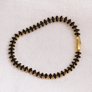 Close-up of gold-plated tennis bracelet with black marquise-cut zircons and fold-over clasp