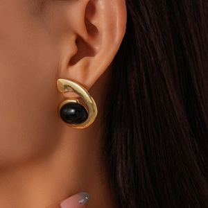 Close-up of vintage gold spiral earrings featuring an oval black gemstone on model