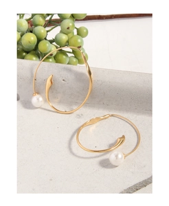 Close-up of golden S925 sterling silver earring with a white pearl on a stone surface