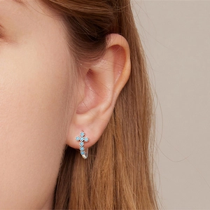 Close-up of S925 silver cross earring with turquoise bead worn on earlobe