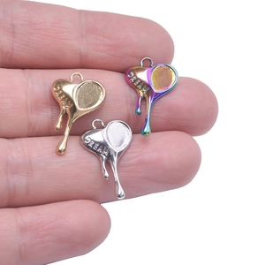 Three heart-shaped DREAM pendants in gold, silver, and rainbow colors on fingertips