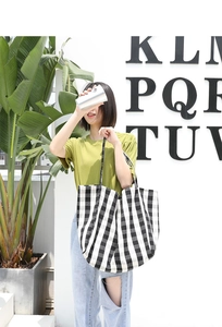 Outdoor shot of a casual black and white checkered canvas tote bag worn by a model