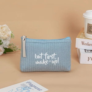 Blue striped canvas makeup bag with handle featuring white but first, make-up text