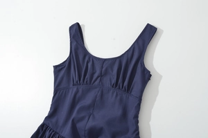 Close-up of ruched pleated detail and waist tailoring on a navy sleeveless dress