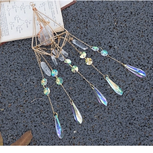Detailed view of crystal suncatcher with golden frame on gravel and vintage book background