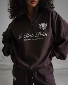 Détail du sweat marron foncé montrant la broderie française et le col à demi-fermeture