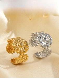Detail of gold and silver stainless steel daisy rings showing petal texture on silk