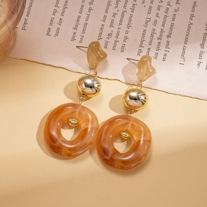 Detail of vintage earrings with beige resin, gold beads and amber rings on newspaper