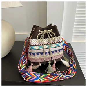 Detail of ethnic bucket bag featuring colorful geometric embroidery and vibrant tassels