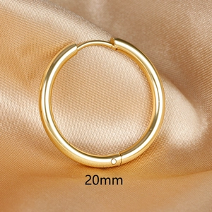 Detailed view of a 20mm gold stainless steel hoop earring on elegant golden silk fabric