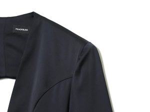 Détail d'une mini robe en satin noir montrant la texture lisse du tissu et l'étiquette du col
