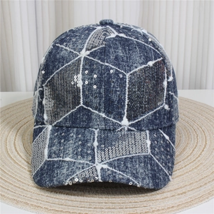 Detailed close-up of blue denim baseball cap with silver sequins on woven mat