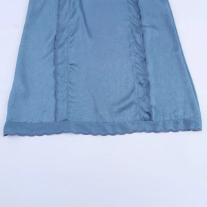 Gros plan d'une robe courte brodée bleue avec tissu plissé et bordure ondulée détaillée