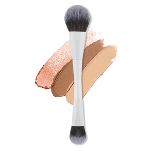 Dual-ended makeup brush with white handle over foundation swatches for contouring and blush