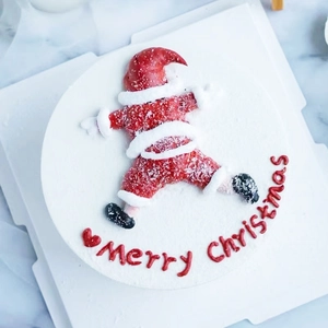 Top view of a soft PVC Santa Claus cake topper with Merry Christmas lettering on white cream