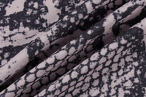 Close-up of animal print knit fabric with fine vertical ribs and glossy snake skin texture