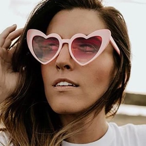 Fashionable pink heart-shaped sunglasses with glitter frame worn by a model outdoors