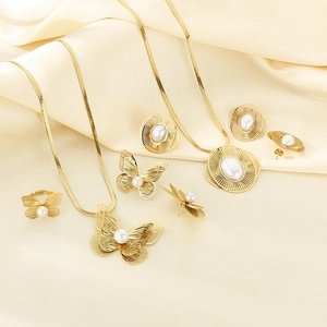 Detail of gold-plated stainless steel jewelry sets with butterfly and pearl accents on silk