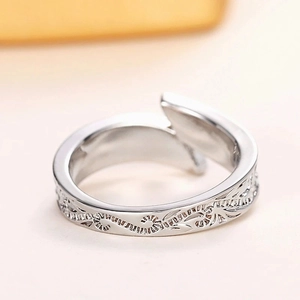 Detailed close-up of a silver bypass feather ring with intricate vine engravings