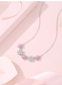 Detail of silver necklace with five pink and white zircon flower pendants on silk