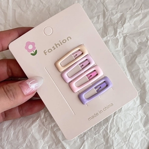 Close-up of four colorful pink and purple star hair clips on a display card