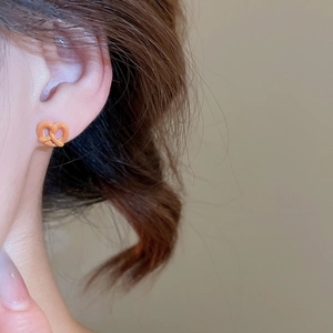 Dettaglio degli orecchini a fiocco arancione con finitura lucida e stile carino