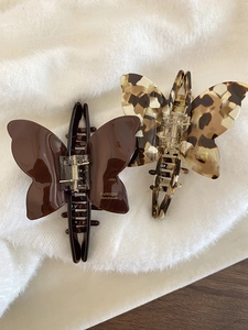 Close-up of brown and leopard print butterfly acetate hair claws on white faux fur