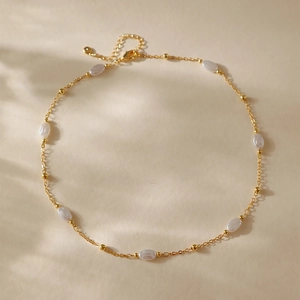 Elegante collana di perle dorate con perle ovali e chiusura a moschettone in luce calda