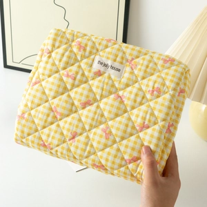 Détail du sac à cosmétiques matelassé vichy jaune avec nœuds roses et étiquette