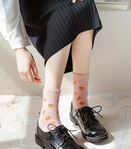 Close-up of pink fuzzy mink velvet socks with orange fruit patterns worn with black shoes