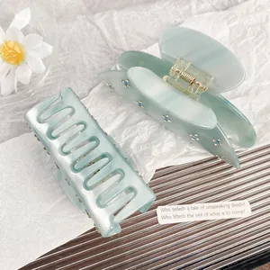 Elegant sky blue acetate hair claw clips with rhinestone flowers set on white background