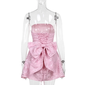 Détail du tissu jacquard rose avec grand nœud et dos nu à lacets sur une mini robe chic