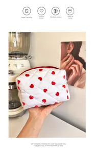 Close-up of quilted white cotton makeup bag with red heart pattern and zipper detail