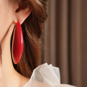 Gros plan d'une grande boucle d'oreille ovale en résine rouge portée par un mannequin