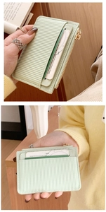 Close-up of light green faux leather coin purse with vertical texture and gold zipper
