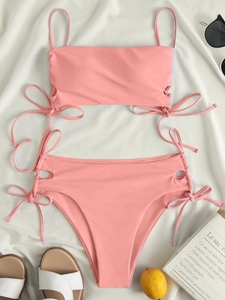 Flat lay of pink high-waisted bikini with side cut-outs and decorative bow ties